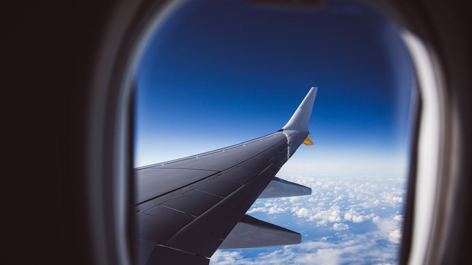 View of an aircraft wing and clouds through an airplane window