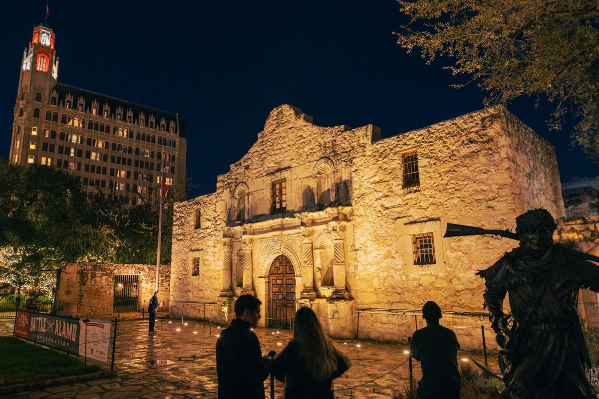 Alamo Plaza lit in the evening with the surrounding downtown buildings