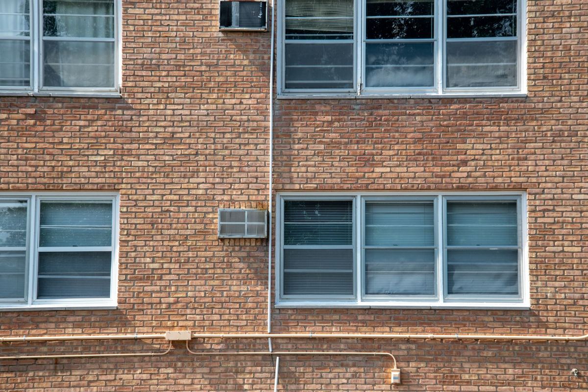 Brick apartment facade with sash windows and a window air-conditioning unit