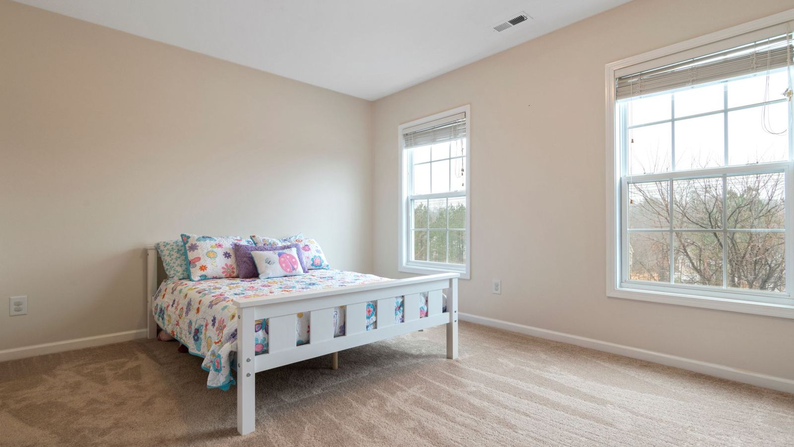 Bright bedroom with daylight from two windows and a single bed