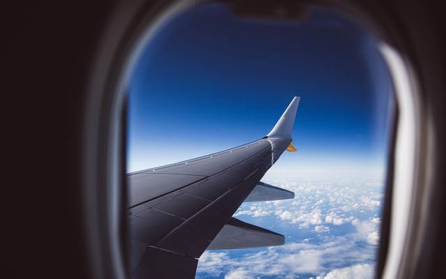 View of an aircraft wing and clouds through an airplane window