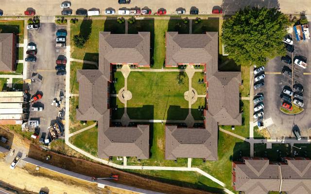Aerial view of a new apartment complex with lawns and surrounding parking