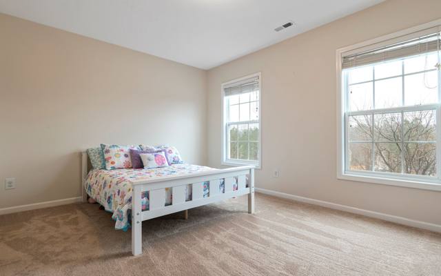Bright bedroom with daylight from two windows and a single bed