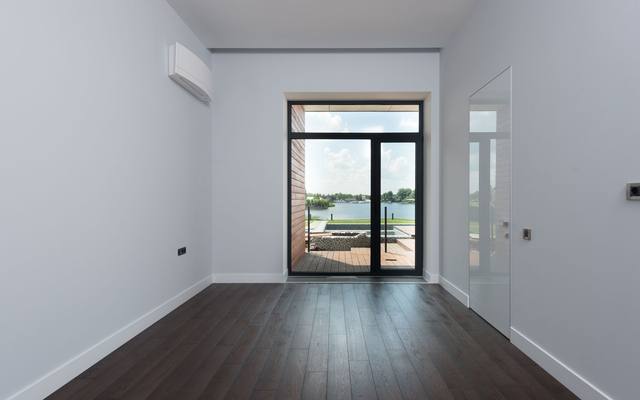 Empty apartment room with wood floors and a full-height balcony door