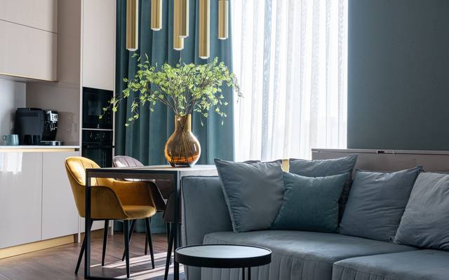 Furnished apartment living area with a teal sofa and a dining table