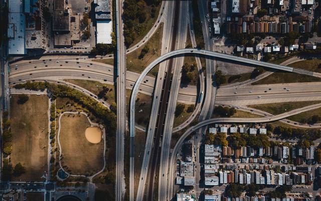 Overhead view of a freeway interchange threading through a dense city grid