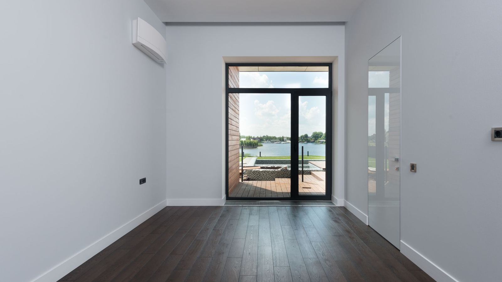 Empty apartment room with wood floors and a full-height balcony door