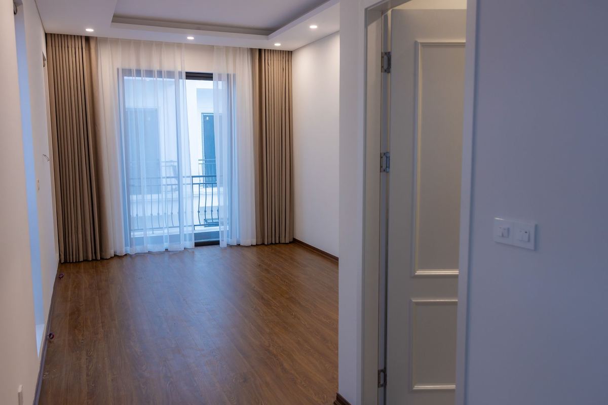 Empty apartment room with sheer curtains at a balcony door