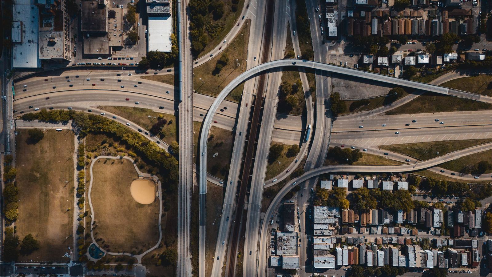 Overhead view of a freeway interchange threading through a dense city grid