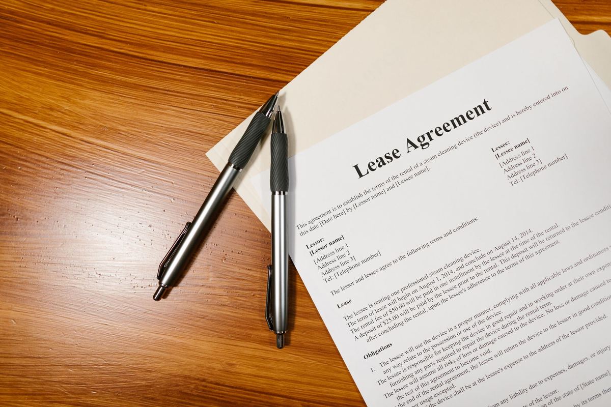 A lease agreement and two pens on a wooden table