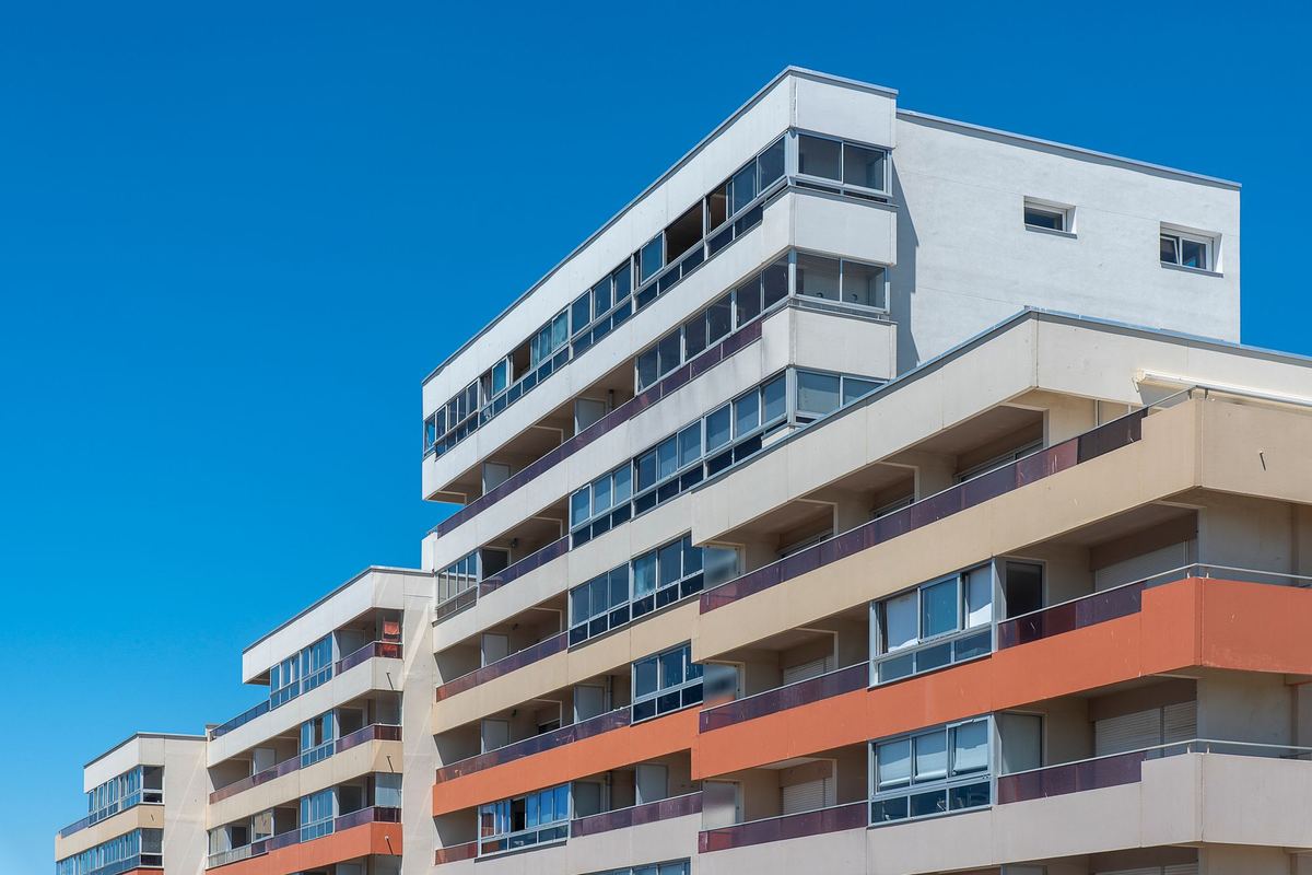 Mid-rise apartment building facade with stacked balconies under a clear sky