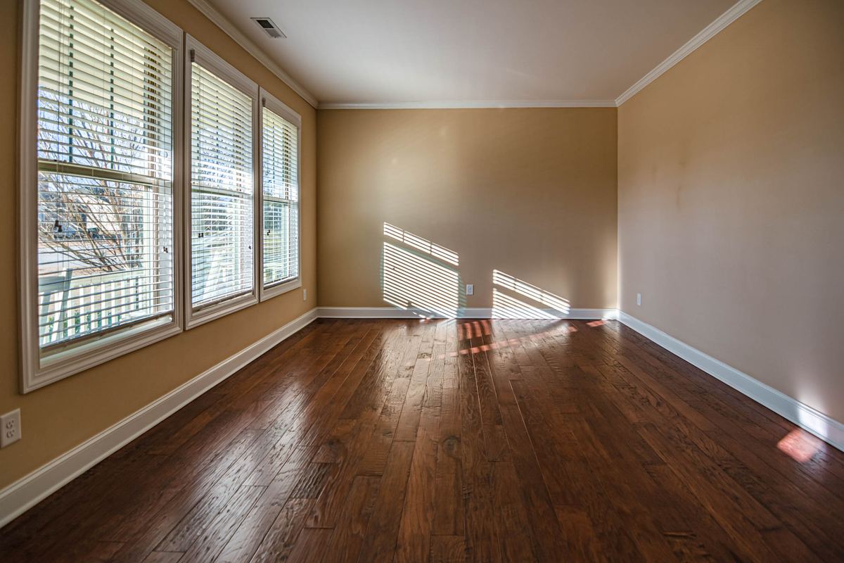 Sunlit empty room with hardwood floors and shuttered windows