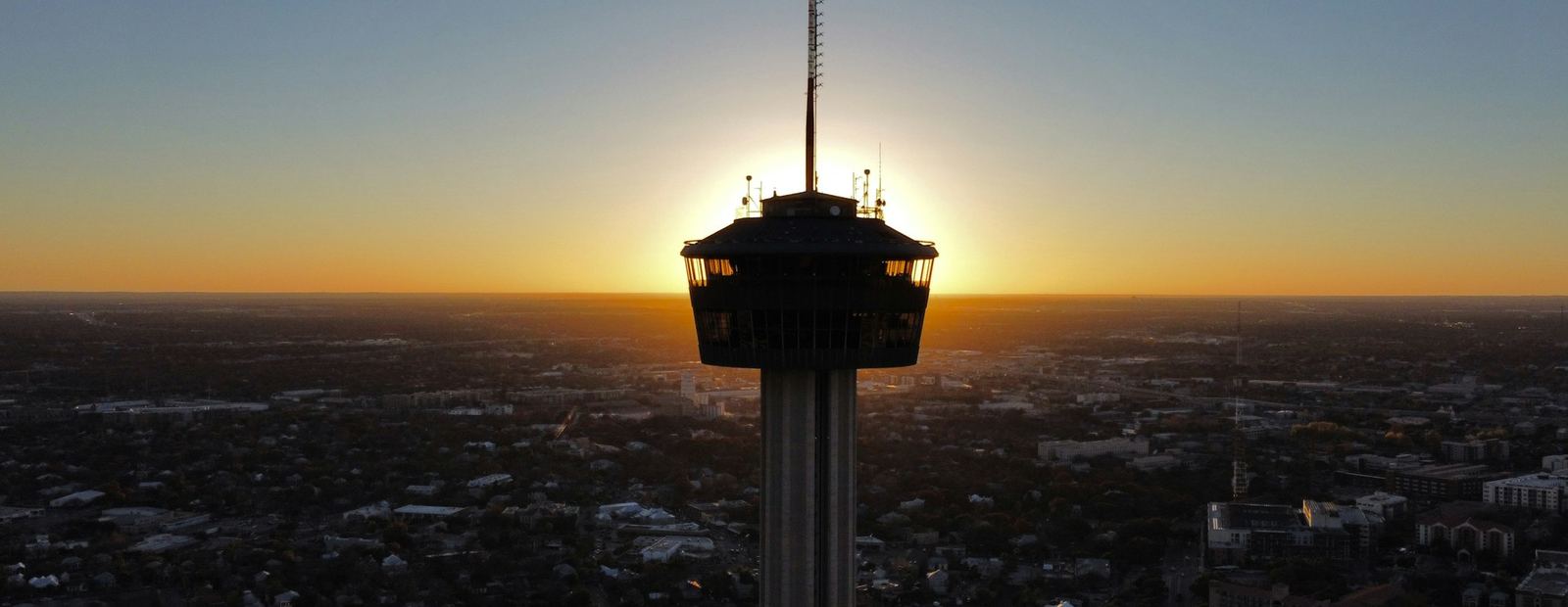 The Tower of the Americas silhouetted against a sunset over San Antonio